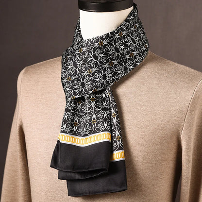 Schwarzer Seidenschal mit weißem Schnörkelmuster und gelber Zierborte, an einer Büste über einem beigen Pullover drapiert. 25