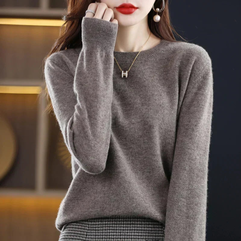 Grauer Pullover mit gerippter Ärmelbündchen, Hand am Kinn, getragen zu einem Hahnentritt-Rock 4