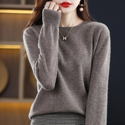 Grauer Pullover mit gerippter Ärmelbündchen, Hand am Kinn, getragen zu einem Hahnentritt-Rock 4