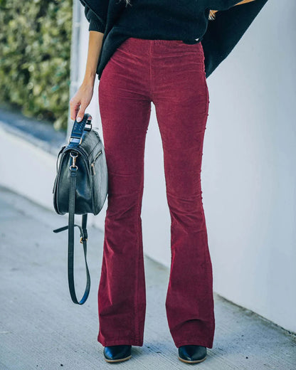 Frau in roten Cord-Schlaghosen, schwarze Tasche, Herbstmode, Straßenstil, Damenbekleidung.