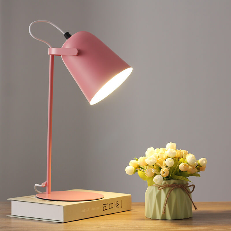 Rosafarbene Tischlampe mit eingeschaltetem Licht steht auf einem Buch neben einem grünen Väschen mit hellen Blüten. 8