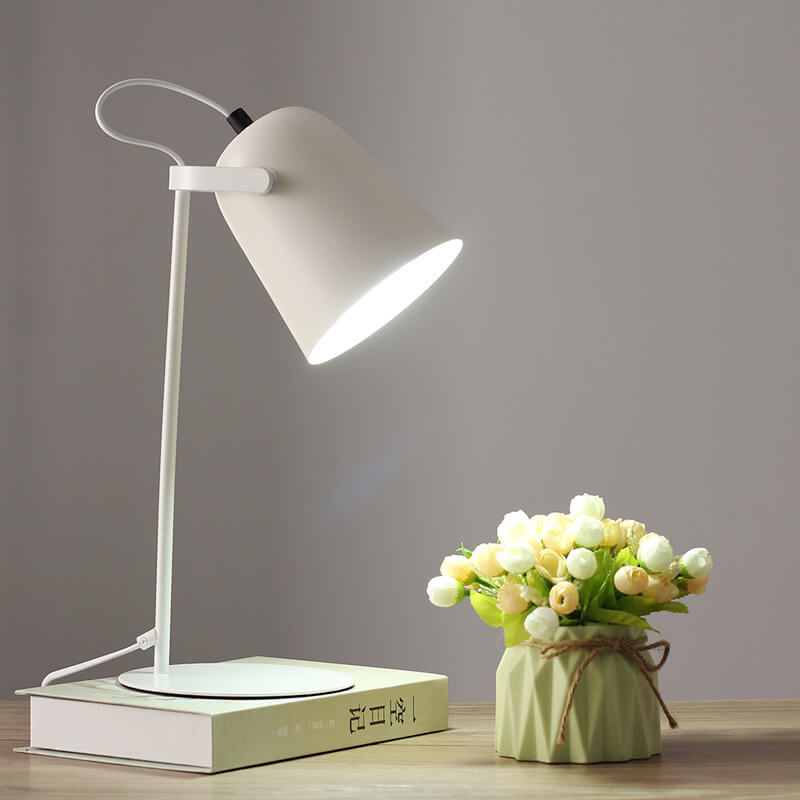 Weiße Tischlampe mit eingeschaltetem Licht steht auf einem Buch, daneben ein grünes Väschen mit Röschen. 11