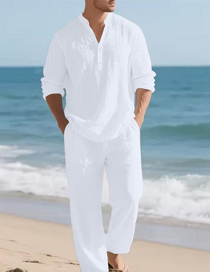 Herren-Leinen-Set in Weiß am Strand, Detail mit Knopfleiste und Händen in den Hosentaschen.