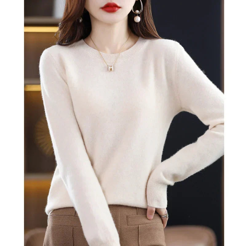 Cremeweißer Pullover mit Rundhals, Hand in die Hüfte gestützt, dazu eine braune Hose 18