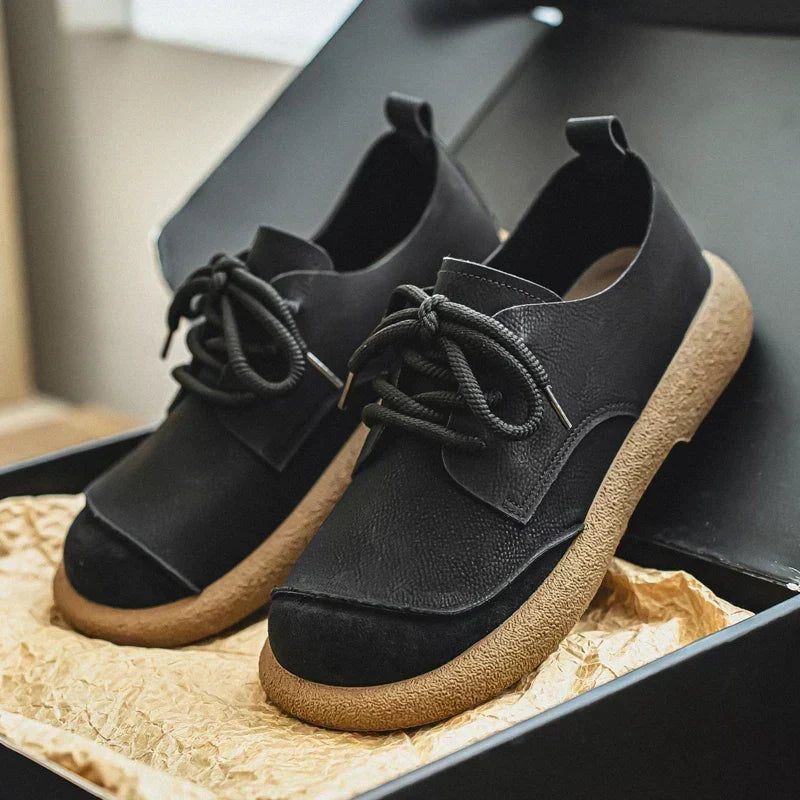 Schwarze orthopädische Komfortschuhe mit heller Gummisohle in einer schwarzen Schachtel.
