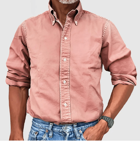Mann in rosa Button-Down-Hemd aus Baumwolle, hochgekrempelte Ärmel, blaue Jeans.