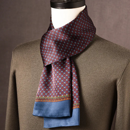 Seidenschal mit rot-blauem Rundmuster und blauer Kante, um eine Schaufensterpuppe mit olivgrünem Pullover geschlungen. 1