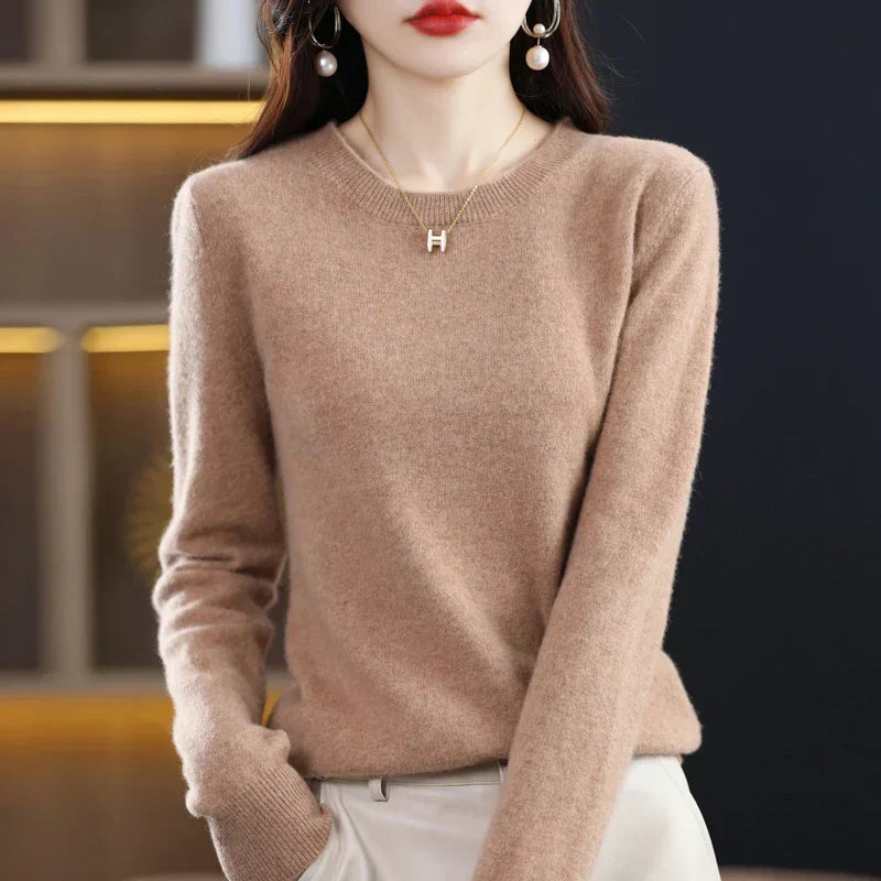 Camelfarbener Pullover mit Rundhals, eine Hand in der Tasche der cremefarbenen Hose 15