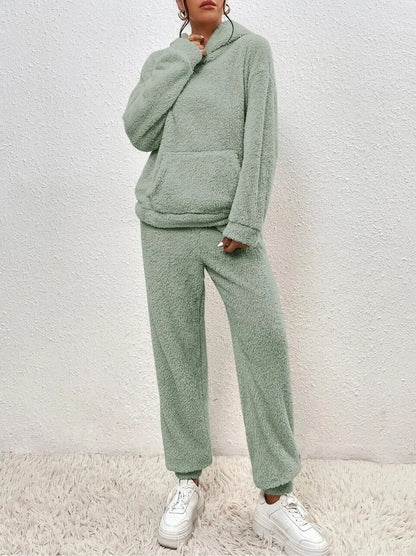 Frau in grünem Fleece-Loungewear-Set, gemütlich, modisch, bequem, auf Teppich stehend.