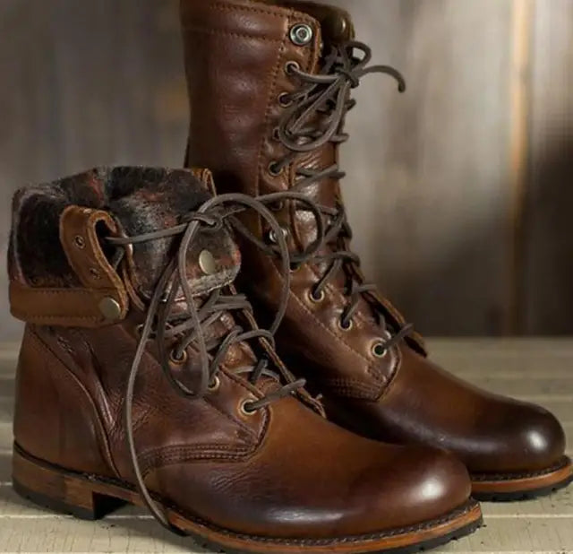 Braune Leder-Schnürstiefel im Paar mit umgeklapptem, gemustert gefüttertem Schaft auf hellem Holzuntergrund.