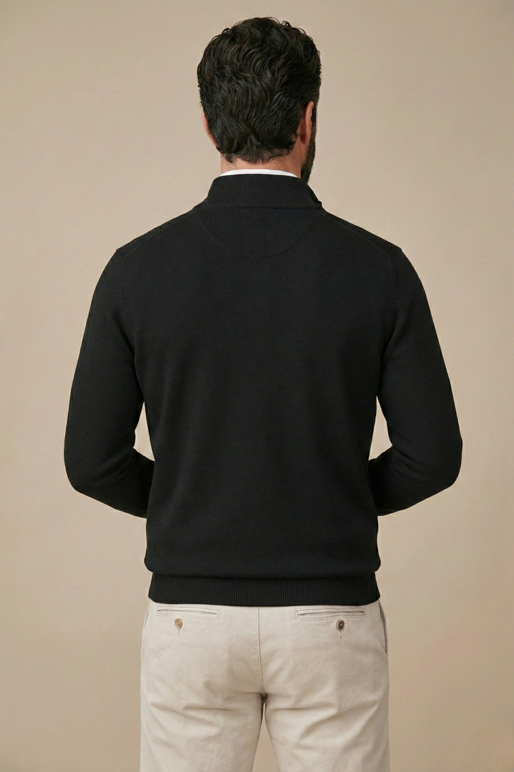 Rückansicht des schwarzen Strickpullovers am Model, mit Rippensaum und Stehkragen, kombiniert mit beiger Hose 2
