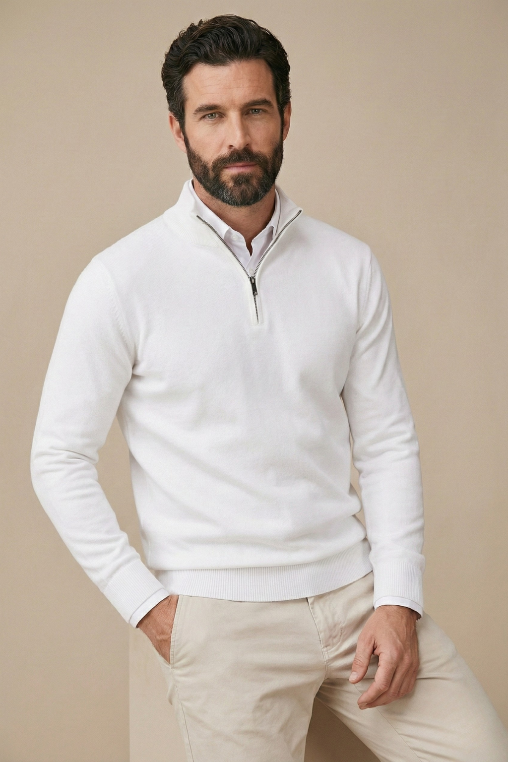 Model in weißem Strickpullover mit Reißverschluss am Kragen, lässig posiert, eine Hand in der beigen Hosentasche 3