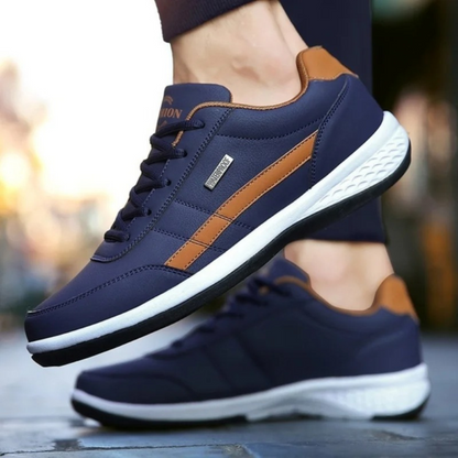 Dunkelblaue Ledersneaker mit orangebraunem Seitenpaneel, getragen beim Gehen.