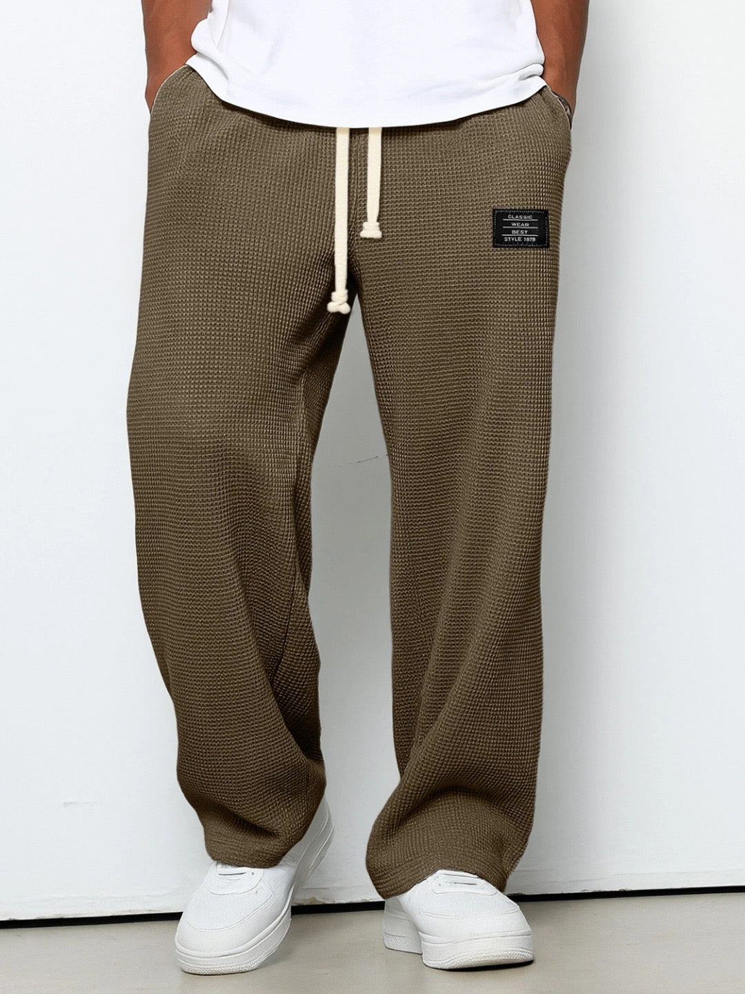 Frontansicht der Hose in Braun-Oliv an einem Model, mit gut sichtbarer Waffelstruktur und Kordelzug. 5