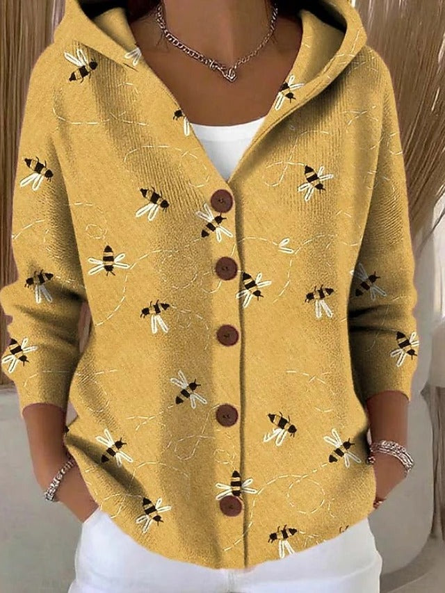 Senfgelbe Kapuzenjacke mit Knopfleiste, getragen über weißem Shirt, bedruckt mit kleinen Bienen und gestrichelten Flugspuren. 2