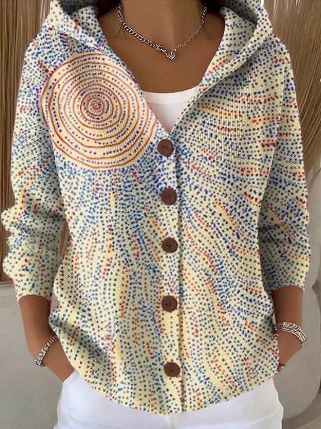 Helle Kapuzenjacke mit Punktmuster in Blau und Orange und einer großen orangefarbenen Spirale als Sonne auf der Schulter. 6