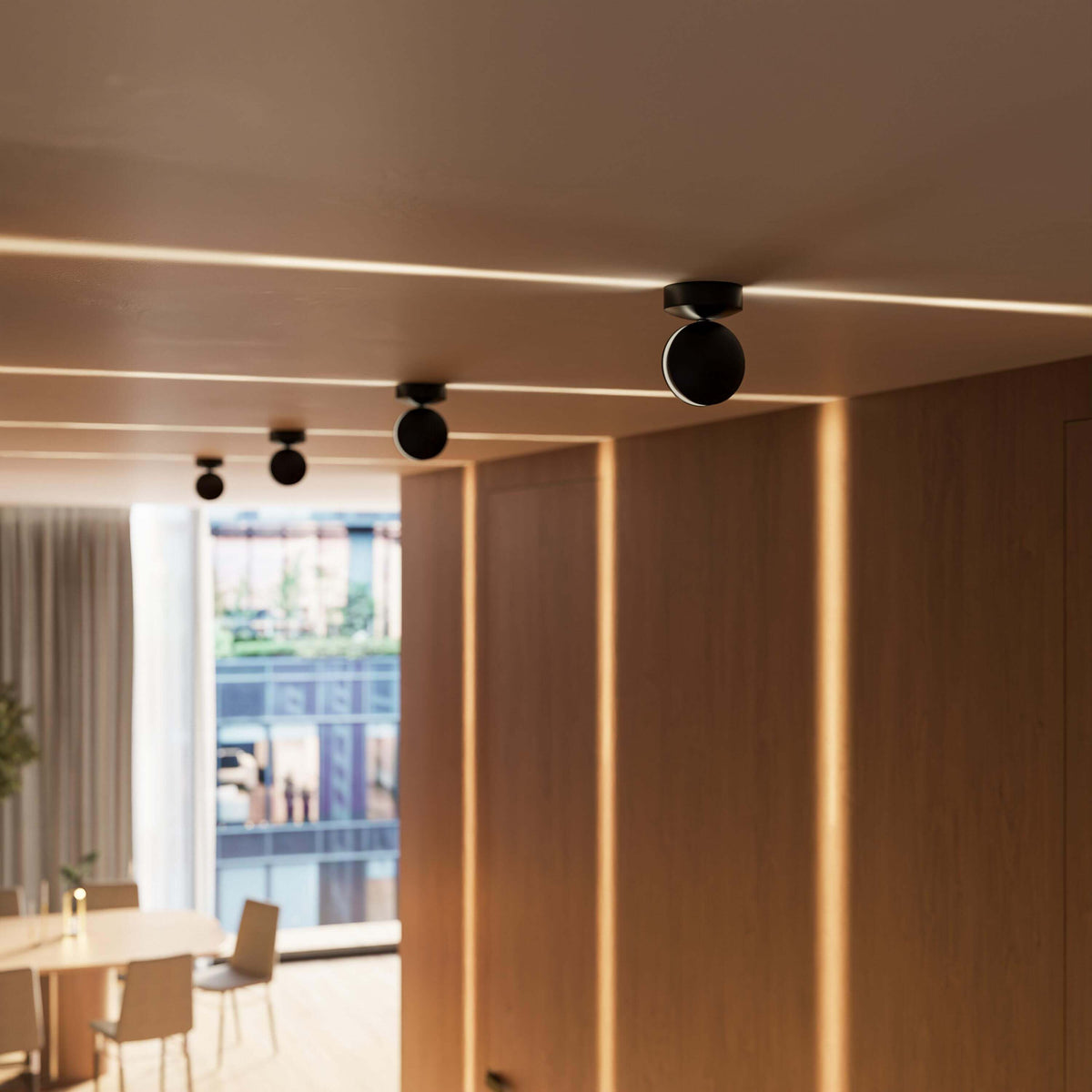 Vier schwarze Deckenleuchten in Reihe an einer Decke, Lichtlinien an Decke und Holzwänden, Esszimmer unscharf im Hintergrund. 12