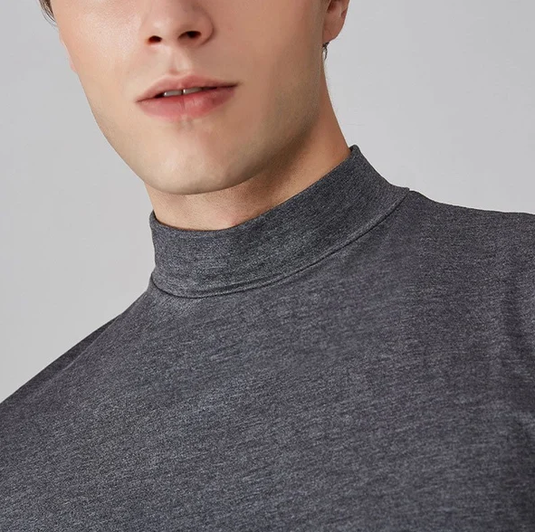 Nahaufnahme des Stehkragens am grau melierten Shirt, getragen von einem Model, Detail vor grauem Hintergrund.