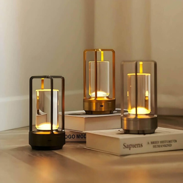 Drei leuchtende Lampen in Schwarz, Gold und Silber stehen auf Büchern und Holzboden in einer Zimmerecke. 2