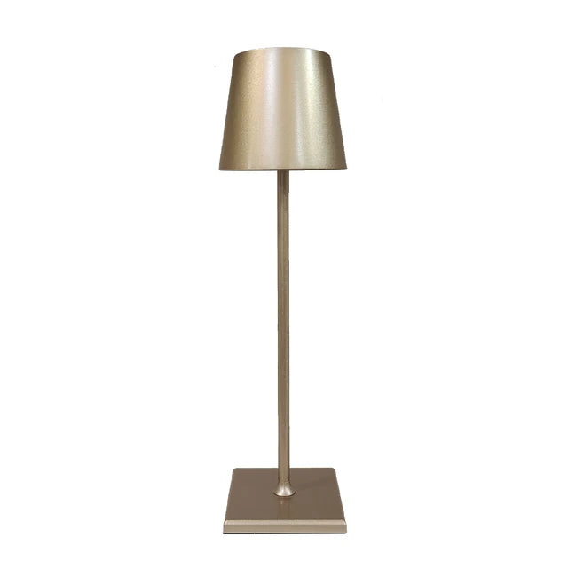 Goldfarbene Tischlampe mit konischem Schirm und quadratischem Fuß vor weißem Hintergrund