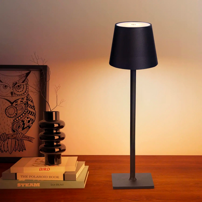 Schwarze kabellose Tischlampe aus Metall mit schlankem Fuß auf einem Holztisch