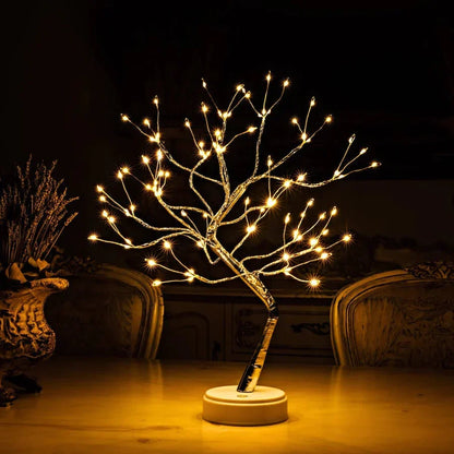 Lichterbaum mit warmen Lichtern auf einem Tisch im Dunkeln, daneben eine Vase mit Trockenblumen 2