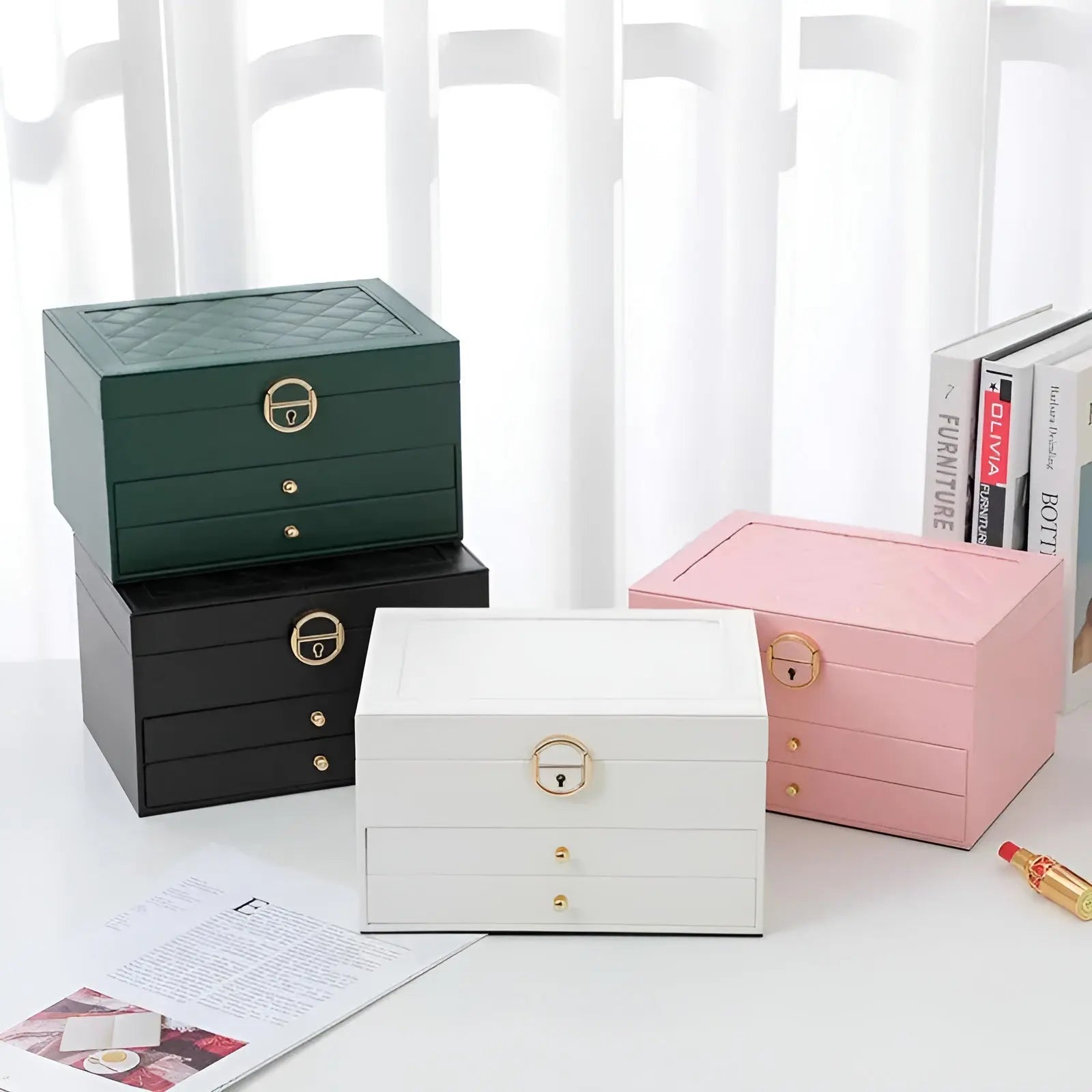 Vier Schmuckkästchen in Grün, Schwarz, Weiß und Rosa, mit Schubladen und goldenen Griffen.