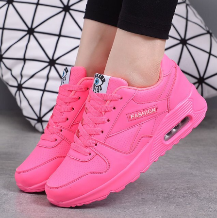 Neonpinke Sneaker mit Luftpolster-Sohle und Schnürung, am Fuß eines Models in Schrägansicht 3
