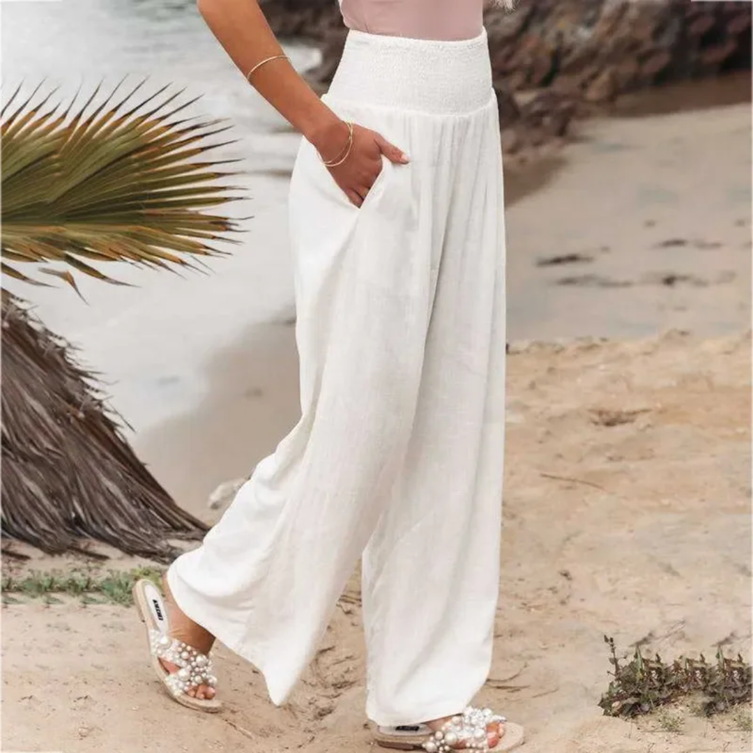 Frau in weißen Leinenhosen am Strand, Sommermode, bequeme Damenbekleidung, lässiger Stil.