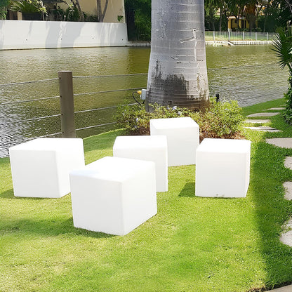 Weiße Würfelhocker aus Kunststoff, Gartenmöbel, modern, am Seeufer auf grünem Rasen.