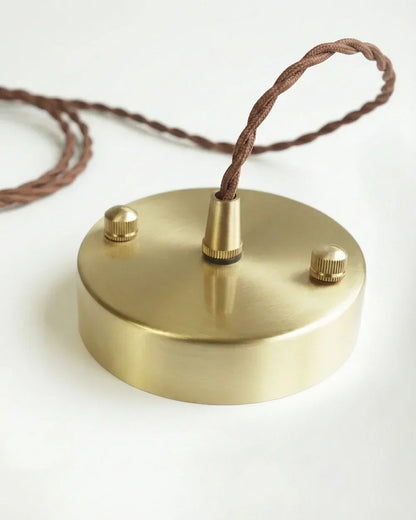 Runde Deckenrosette aus gebürstetem Messing mit braunem, gedrehtem Stoffkabel.