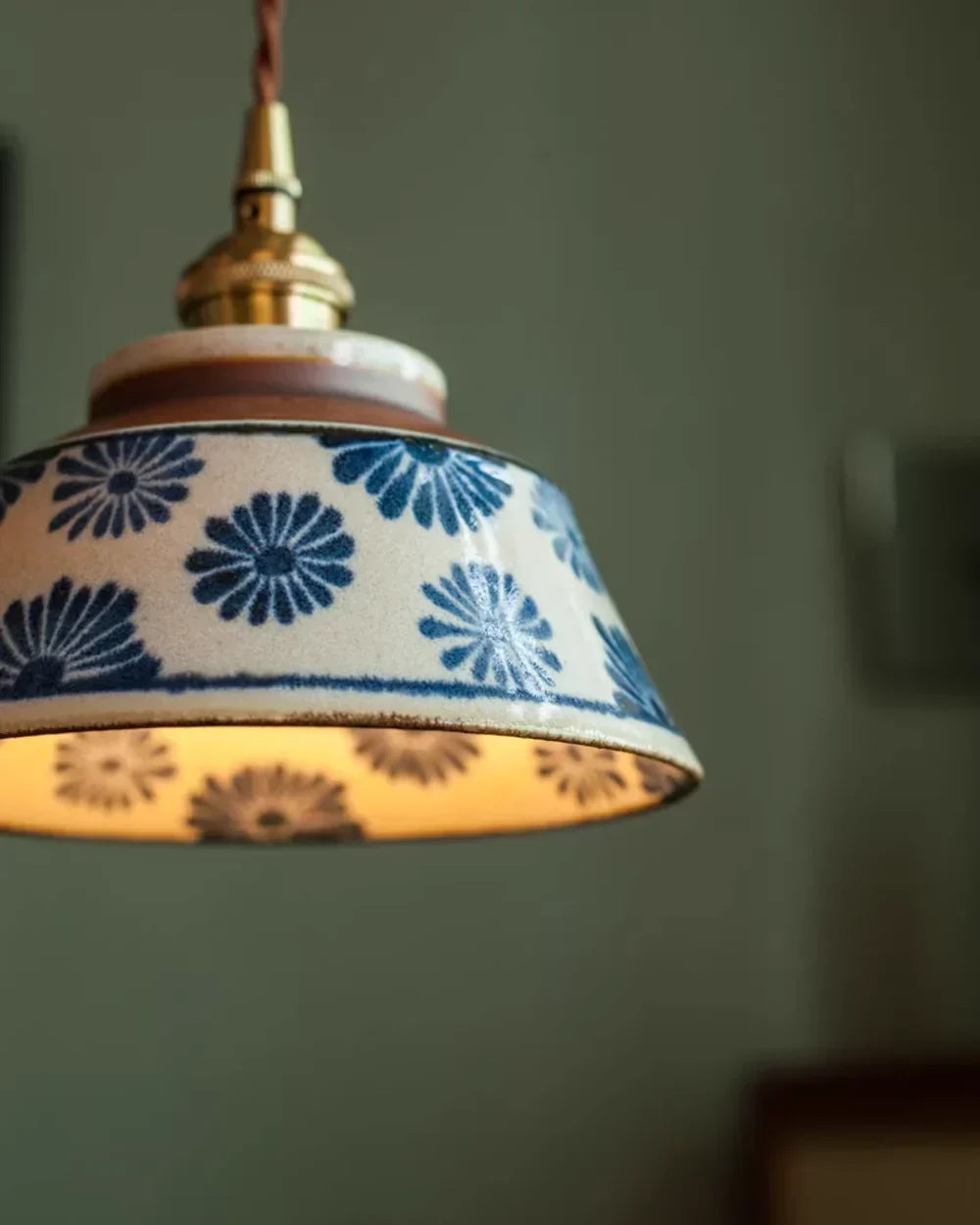 Nahaufnahme der Keramik-Pendelleuchte mit blau geblümtem Schirm und glasierter Oberfläche.