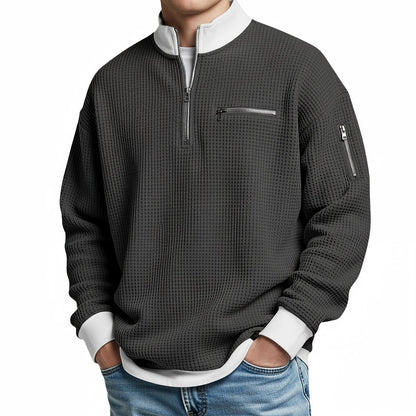 Herrenpullover in Anthrazit mit Viertel-Reißverschluss und weißem Stehkragen, frontal am Model.
