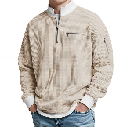 Herrenpullover in Beige mit Reißverschluss am Kragen und weißem Stehkragen, frontal am Model.