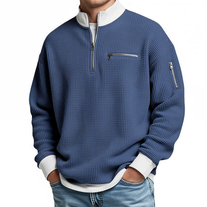 Herrenpullover in Blau mit weißem Stehkragen, Reißverschluss und sichtbaren Taschen, detail.