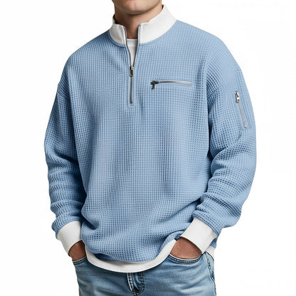 Herrenpullover in Hellblau mit Viertel-Reißverschluss und weißen Bündchen, frontal am Model.
