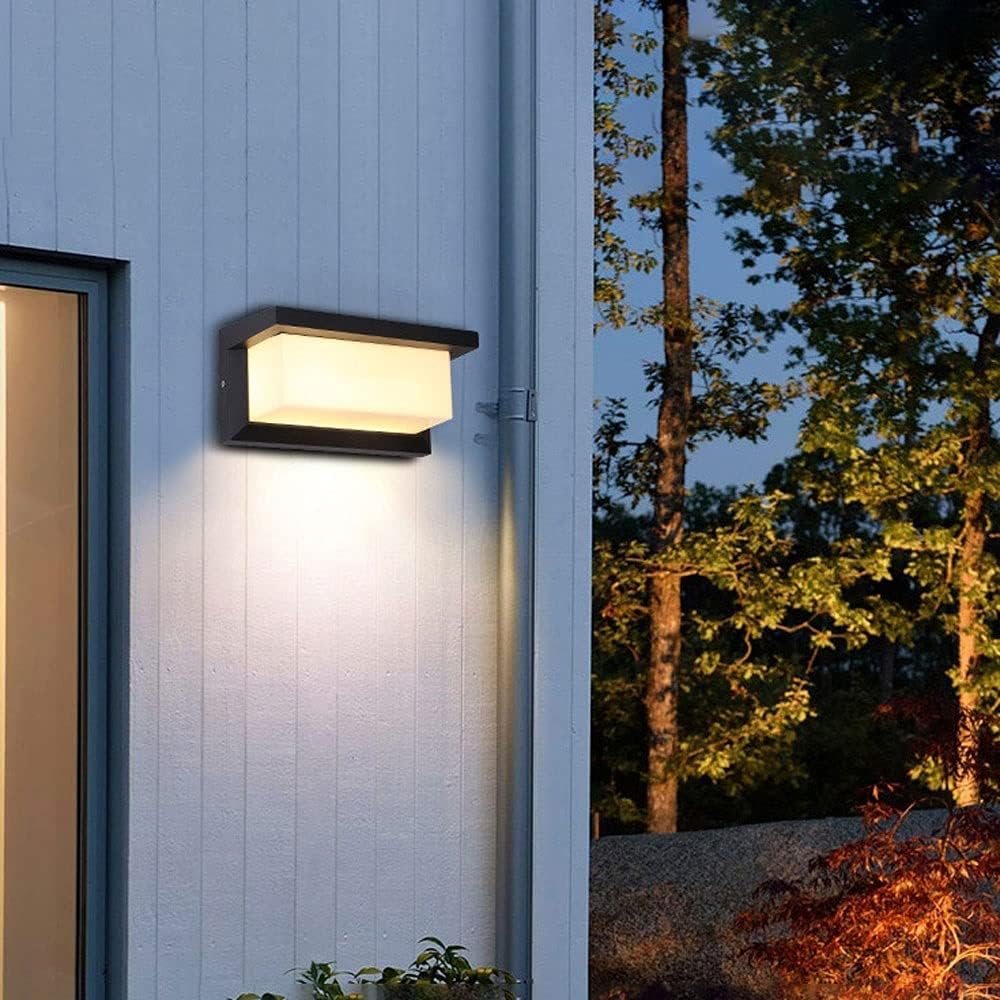 Leuchtende Wandleuchte an hellblau gestrichener Holzwand neben einem Fenster, im Hintergrund Bäume bei Nacht 6