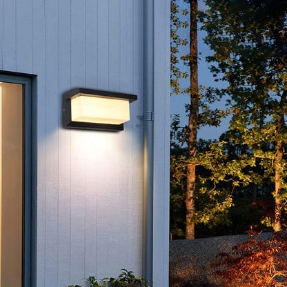 Leuchtende Wandleuchte an hellblau gestrichener Holzwand neben einem Fenster, im Hintergrund Bäume bei Nacht 6