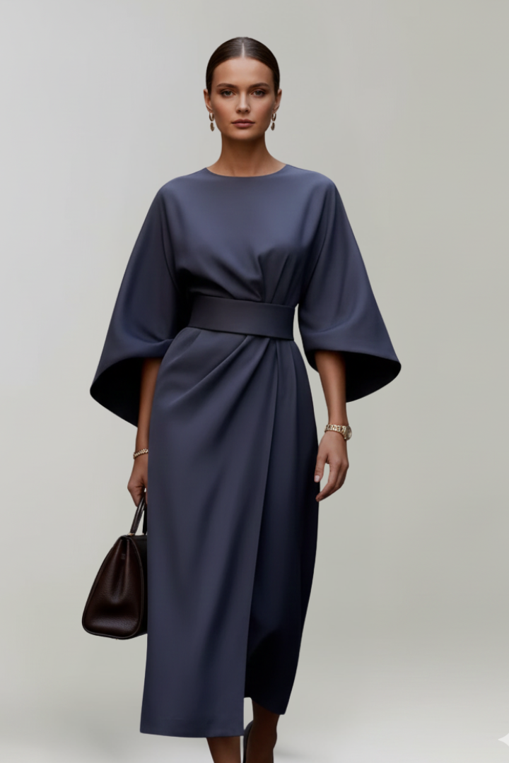 Model in dunkelblauem Kleid frontal, mit brauner Handtasche und weiten Ärmeln, die bis zum Ellenbogen reichen 2