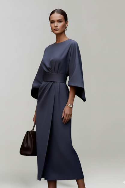Dunkelblaues Kleid im Dreiviertelprofil am Model, Wickelrock mit Schlitz, Gürtel in der Taille, dunkle Handtasche in der 3