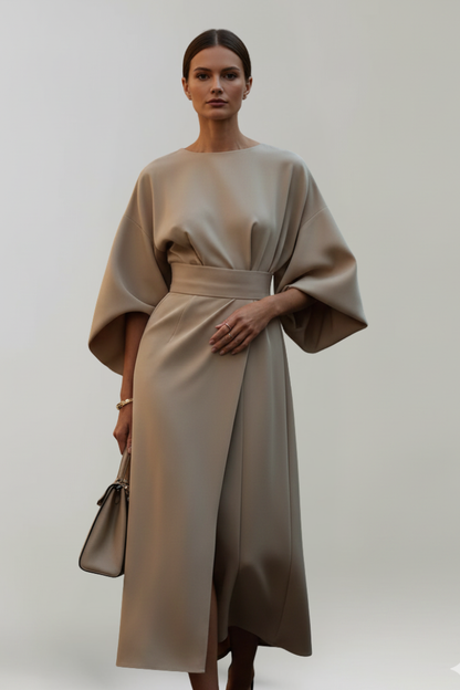 Model im beigefarbenen Kleid mit weiten Ärmeln, Taillengürtel und seitlichem Wickelrock, dazu eine helle Handtasche 6