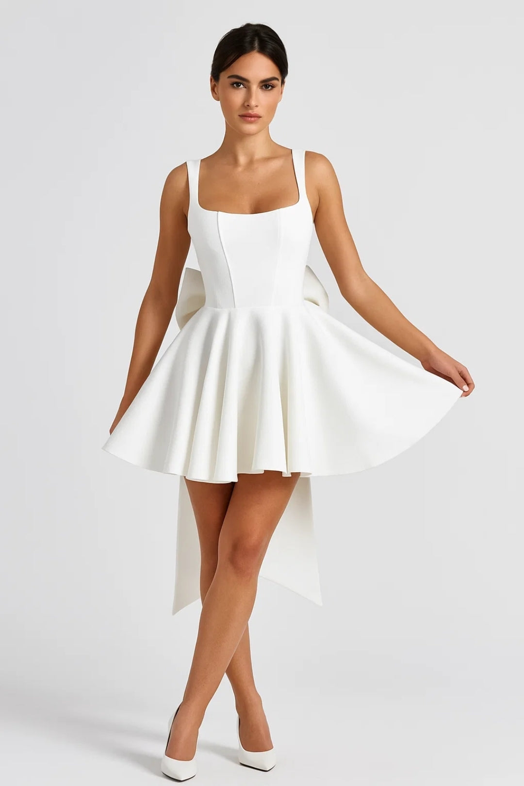 Model in weißem Minikleid mit ausgestelltem Rock, von vorn, hält den Rocksaum seitlich hoch 3