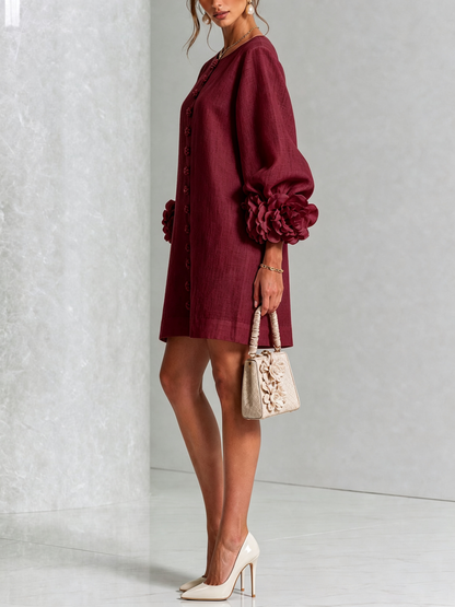 Weinrotes Minikleid seitlich getragen, Blumenknöpfe an der Front, Rosenmanschette am Puffärmel, cremefarbene Handtasche mit Blumenapplikationen und Pumps. 36