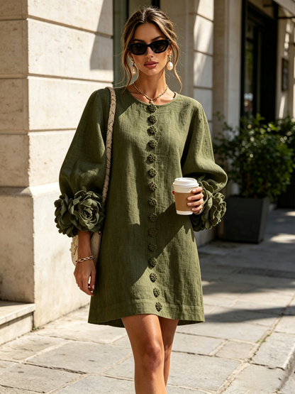 Das olivgrüne Kleid im Straßenlook mit Sonnenbrille, geflochtener Umhängetasche und Kaffeebecher vor heller Steinfassade. 10