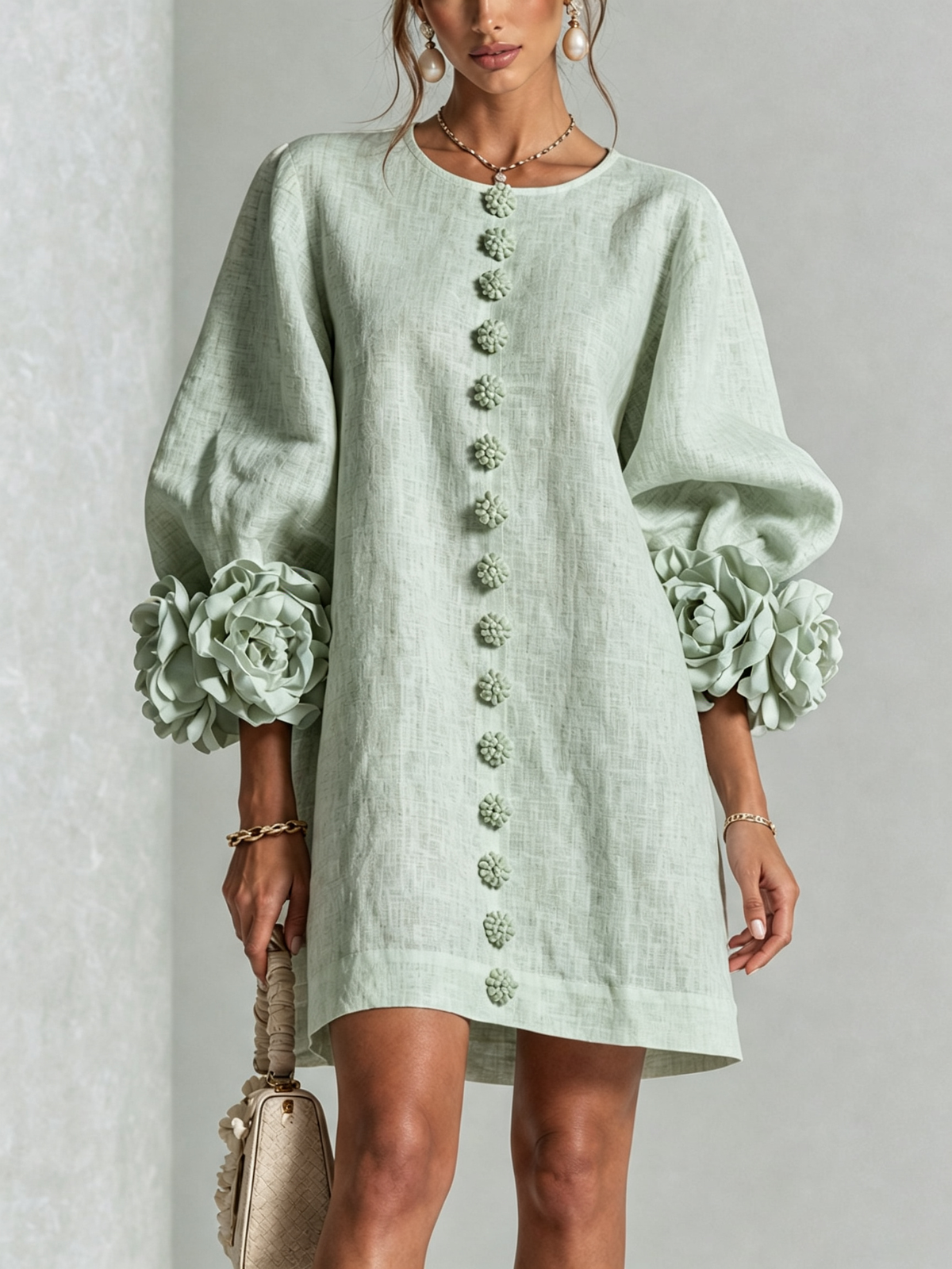 Mintgrünes Minikleid in Nahaufnahme von vorn, Blumenknopfleiste, weite Puffärmel mit großen Rosenmanschetten, Perlenohrringe und Handtasche. 31