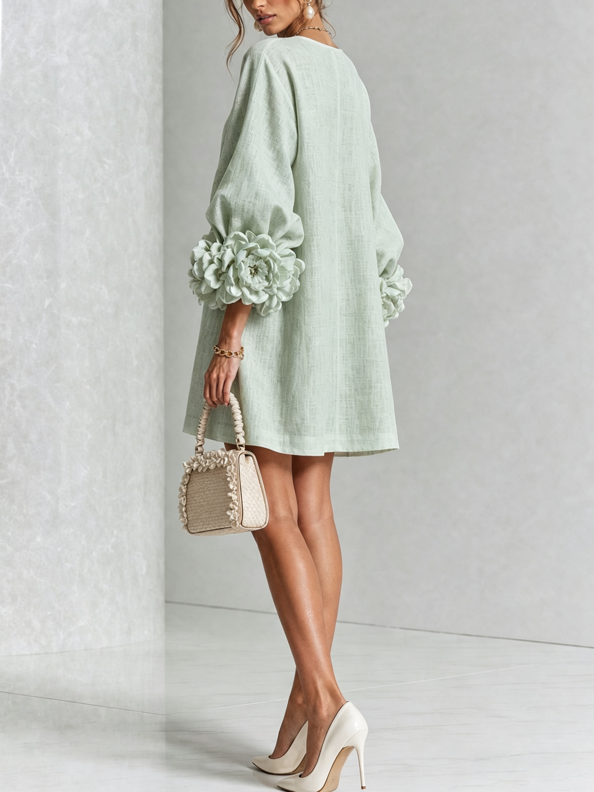 Mintgrünes Minikleid von hinten getragen, schlichter Rücken, Puffärmel mit Rosenmanschetten, Handtasche mit Rüschenrand vor Marmorwand. 33