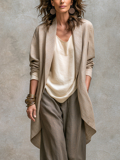 Nahaufnahme des offenen langen Jacketts in Beige mit Schalkragen und abgerundetem Saum, getragen über dem cremefarbenen Oberteil. 3