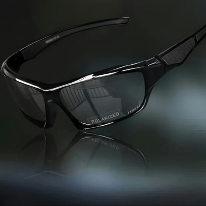 Komplett schwarze Sportbrille mit grau getönten Gläsern, schräg vor dunklem Hintergrund mit Spiegelung 10