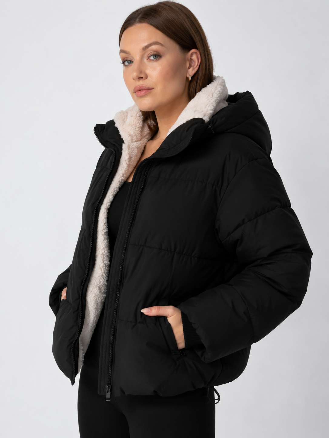 Schwarze Steppjacke seitlich fotografiert, Kapuze mit hellem Teddyfleece, Tunnelzug am Saum sichtbar 12
