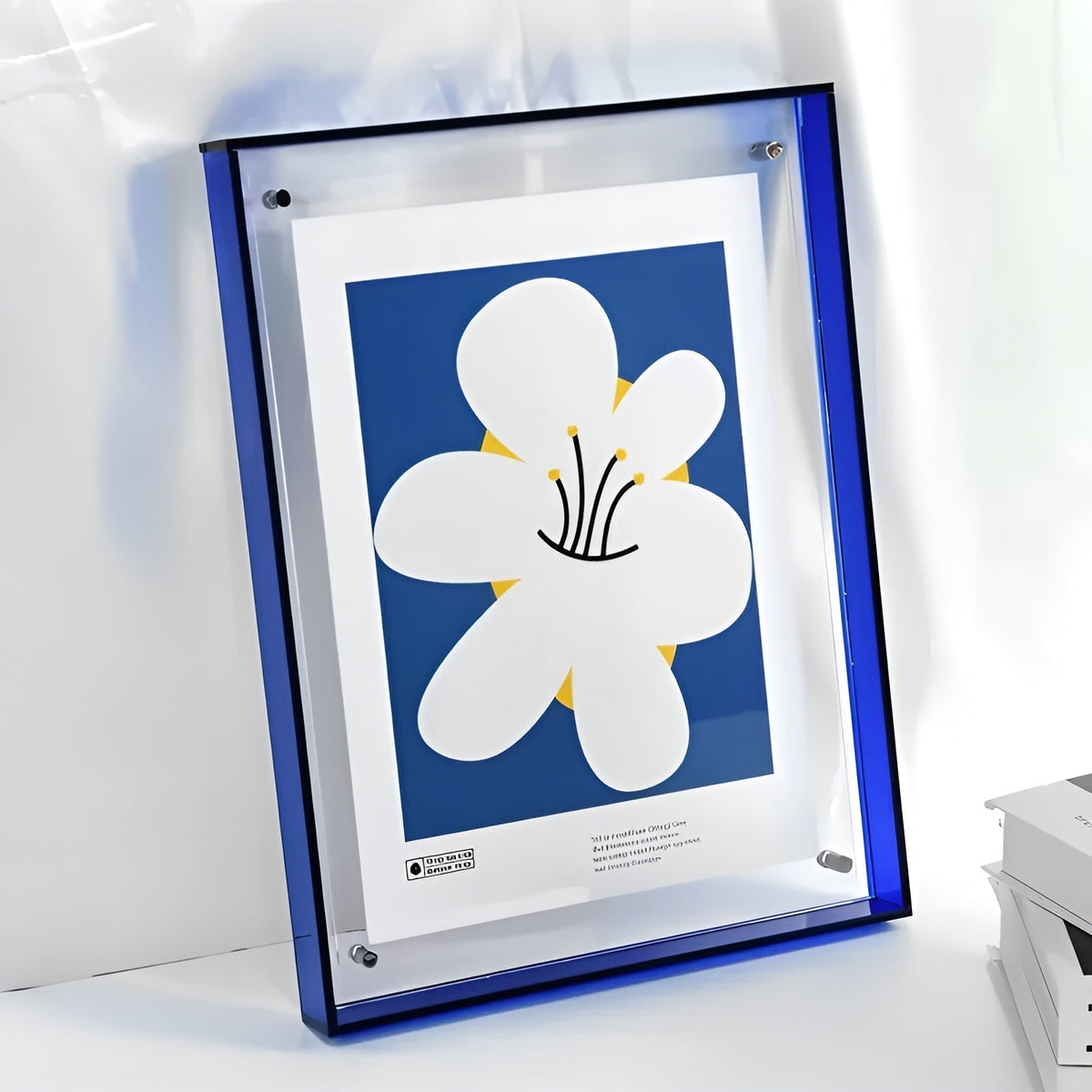 Acrylrahmen mit blauem Rand und schwarzer Oberkante, darin ein Plakat mit großer weißer Blume